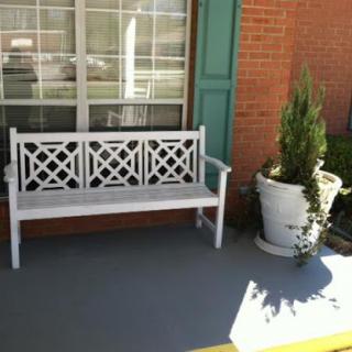 A charming outdoor scene featuring a white bench and potted plants.