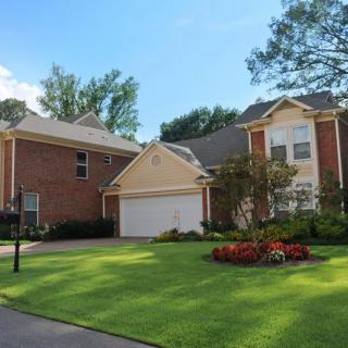 A suburban house with a neatly maintained lawn and a driveway.