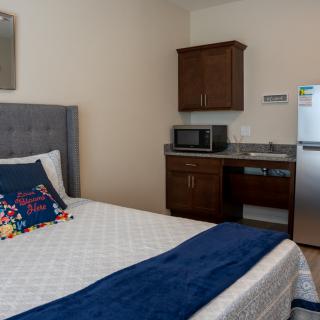 A cozy hotel room with a bed, microwave, and refrigerator.