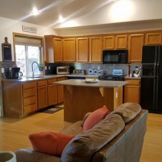 A modern kitchen with wooden cabinets and an island counter, featuring various appliances and an open layout.