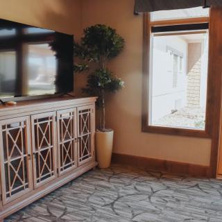 A cozy living room corner with a stylish cabinet and TV, complemented by a potted plant and natural light from the window.