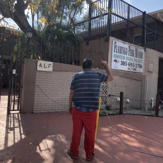 A person standing outdoors near a building and a sign.