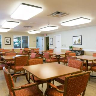 An empty dining area with neatly arranged tables and chairs, well-lit by overhead lighting.