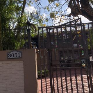 A gated entrance with an address sign leading to a house surrounded by trees.