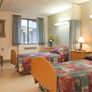 A hospital room with two beds, a window, and cozy lighting.