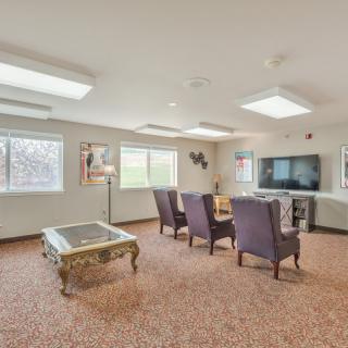 A spacious living room with several upholstered chairs, a coffee table, and a large television.