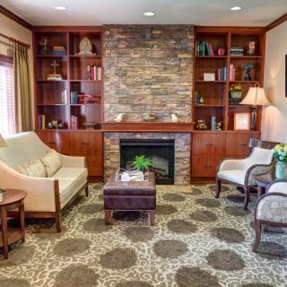 A cozy living room with a stone fireplace, built-in shelves, and comfortable seating.