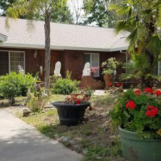 A charming house surrounded by a lush garden with vibrant flowers and greenery.