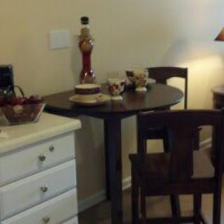 A cozy dining area with a small table and two chairs, adorned with a lamp and decorative items.