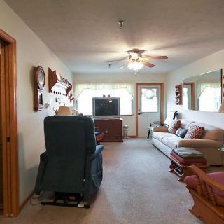 A cozy living room featuring a sofa, television, and ceiling fan with natural light flowing from the windows.