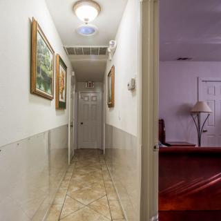 A well-lit hallway with artwork on the walls and tiled flooring.
