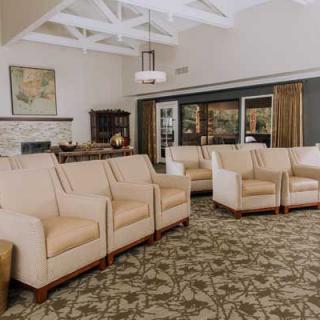 A modern lobby with beige armchairs and a patterned carpet.