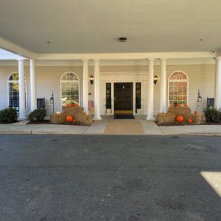 A building entrance decorated with autumn-themed elements, including pumpkins and hay bales.