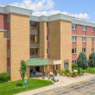 A multi-story apartment building with a landscaped entrance and clear blue skies.