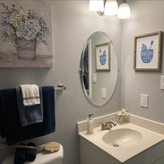 A neatly organized bathroom with a mirror, sink, and decorative wall art.