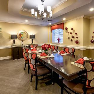 A modern dining room with a beautifully set table, featuring red and white accents and stylish wall decorations.