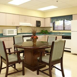 A kitchen and dining area featuring a round table with chairs, a microwave, refrigerator, and countertop appliances.