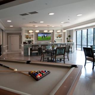 A modern game room with a billiard table, bar, and seating area.