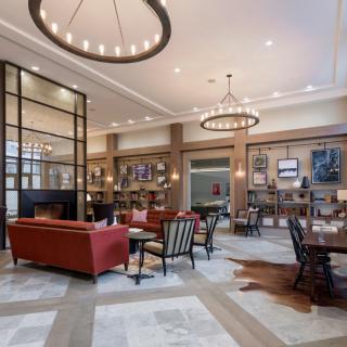 A warmly decorated lobby featuring elegant chandeliers, comfortable sofas, and a library area.