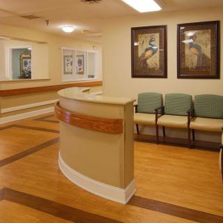 A hospital or clinic waiting room with a reception desk and chairs.