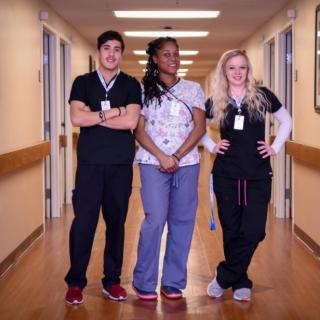 Three healthcare professionals standing together in a hospital corridor.