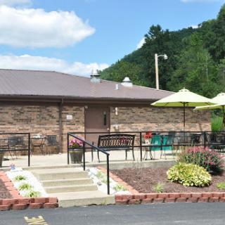 A cozy restaurant with outdoor seating, surrounded by beautiful landscaping and mountain views.