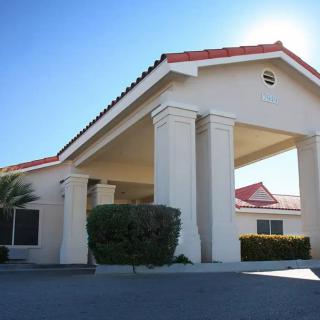 A building with a red-tiled roof and large entrance columns under a clear blue sky.