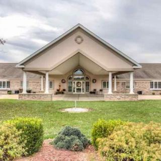 A well-maintained building with a prominent entrance and landscaped surroundings under a cloudy sky.