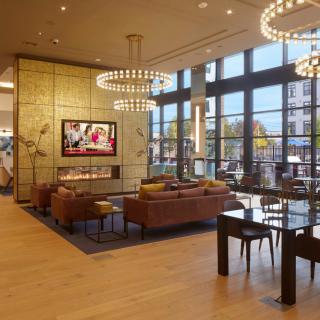 A modern lobby with comfortable seating, elegant chandeliers, and large windows.