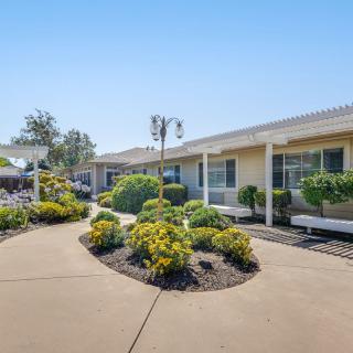 A single-story building with a well-maintained pathway and landscaping under a clear blue sky.