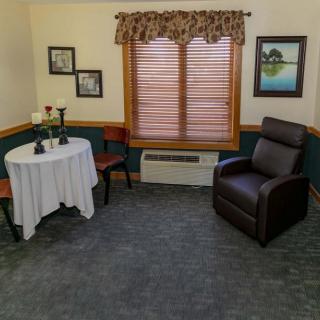 A cozy living room setup with a table and chairs, an armchair, and framed pictures on the walls.