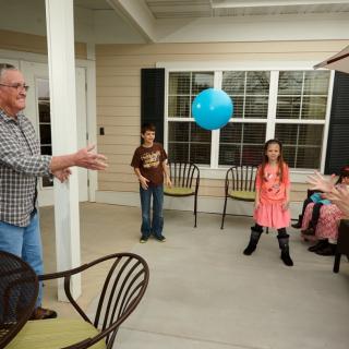 A family enjoys playing with a balloon on the patio.