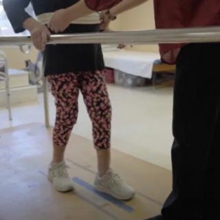 A person undergoing physical therapy using support bars for balance.