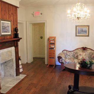 A cozy vintage living room featuring a fireplace, chandelier, and elegant furnishings.