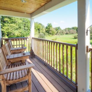 A serene porch with wooden chairs overlooking a lush green landscape.