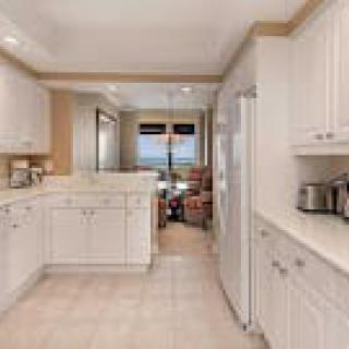 A modern kitchen with white cabinets and appliances, featuring a cozy seating area in the background.