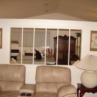 A cozy living room with beige couches and a view into the kitchen through a mirror.