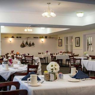 A cozy restaurant dining room with elegantly set tables and warm lighting.