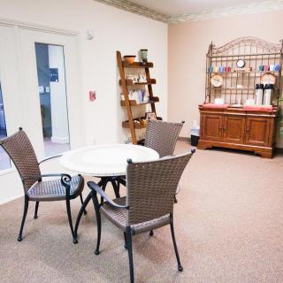 A cozy indoor seating area with a table and chairs, shelves, and decorative elements.