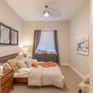 A cozy bedroom with warm lighting and neatly arranged furnishings.