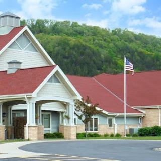 A charming building with a red roof and an American flag, set against a lush green hillside.