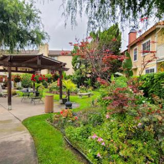 A serene garden with lush greenery and blooming flowers, inviting relaxation under the cloudy sky.