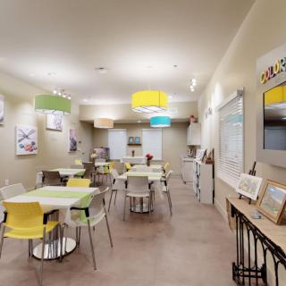 Modern cafe interior with colorful chairs and artwork on the walls.