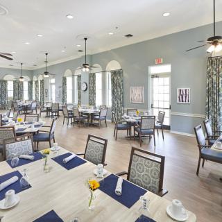 A spacious dining room with neatly arranged tables and chairs, featuring elegant decor and ample natural lighting.