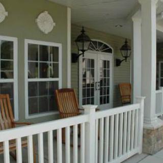 A cozy porch setup with wooden chairs and lanterns flanking French doors.