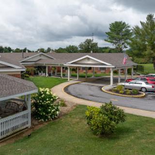 A welcoming residential building surrounded by lush greenery under a cloudy sky.