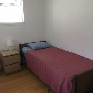A minimalist bedroom with a single bed, nightstand, and lamp.
