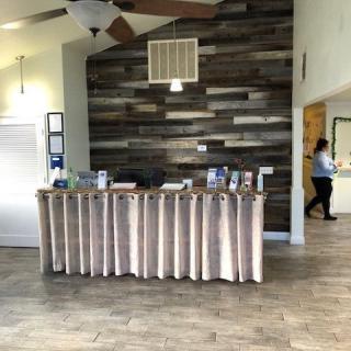 A modern office reception desk with a wooden accent wall in the background.