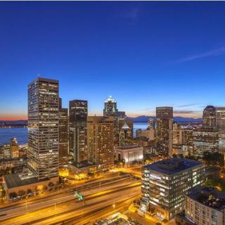 A stunning view of a city skyline illuminated at night, showcasing tall buildings and vibrant lights against a clear sky.