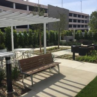 A serene outdoor space featuring benches, greenery, and a grill area, perfect for relaxation and gatherings.